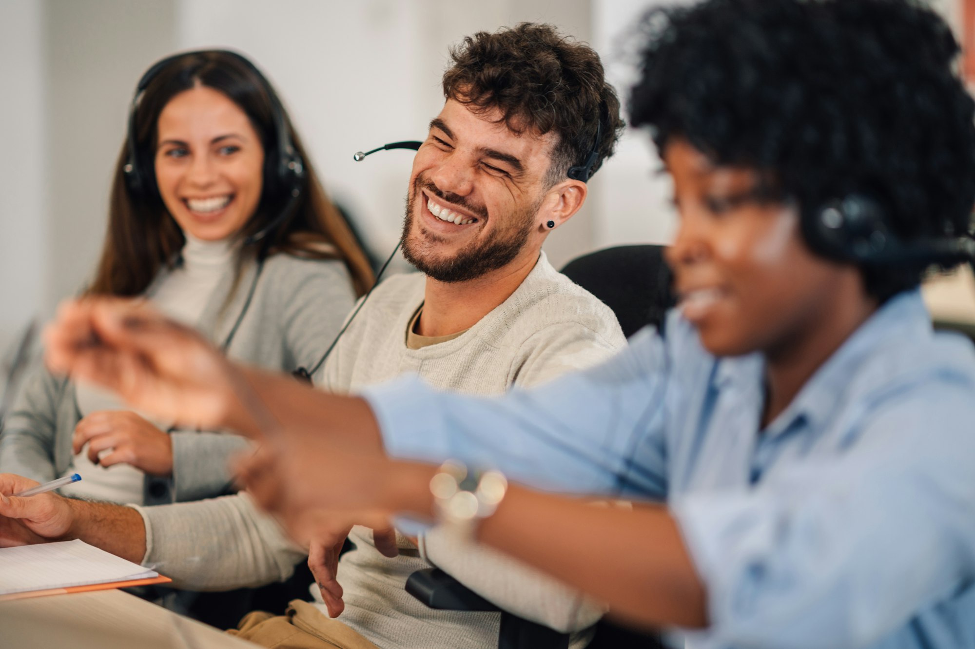 A happy customer support agent is laughing at the office with colleagues.