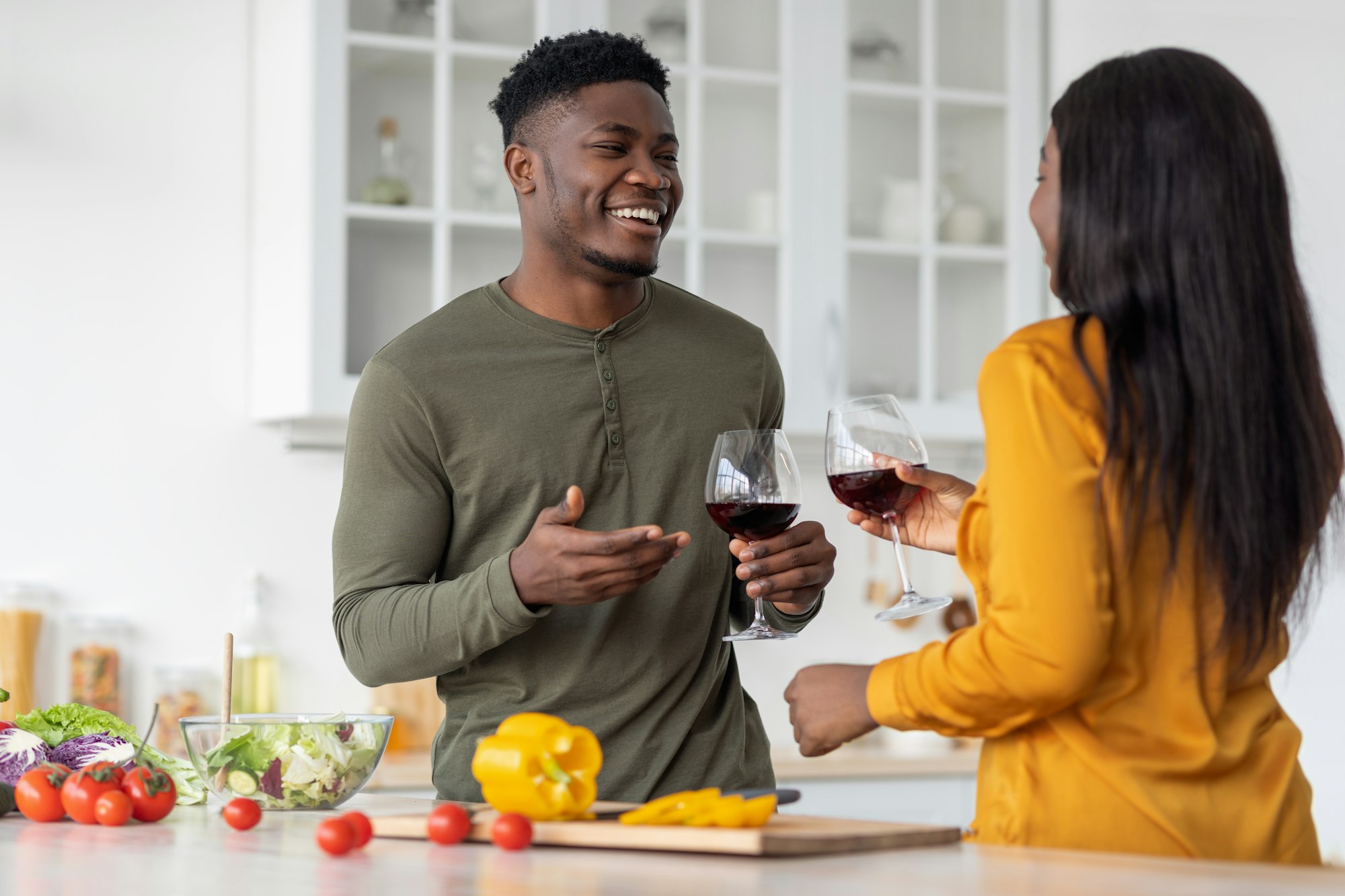 Aperitif Drink. Cheerful Black Man And Woman Drinking Red Wine In Kitchen